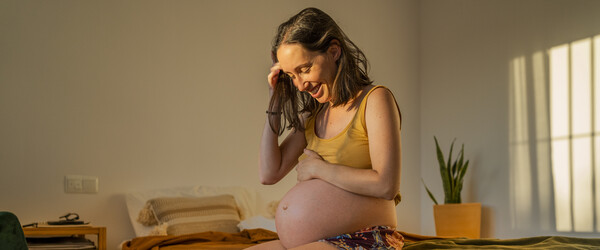 A woman smiling down at her pregnant belly.